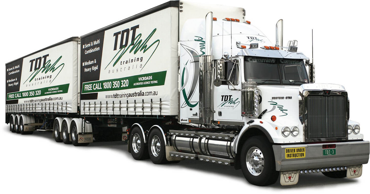 A large white semi-truck with two trailers displays "TDT Training Australia" and a phone number in green. The truck conveys a professional and robust tone.